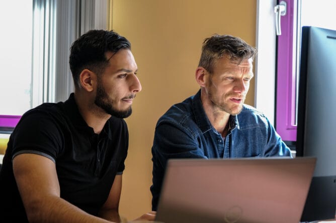 Twee medewerkers achter een computer